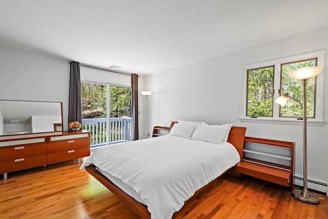 bedroom with visible vents, access to exterior, wood finished floors, and a baseboard radiator