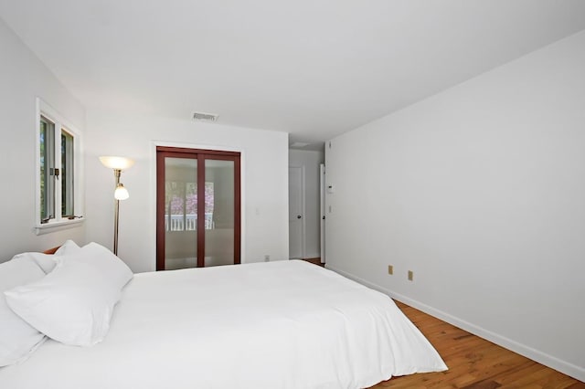 bedroom featuring baseboards, wood finished floors, and visible vents