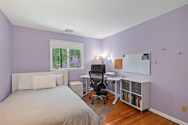 bedroom featuring visible vents, a baseboard radiator, baseboards, and wood finished floors