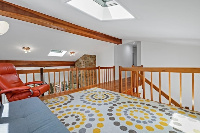 sitting room with lofted ceiling with skylight, wood finished floors, and an upstairs landing