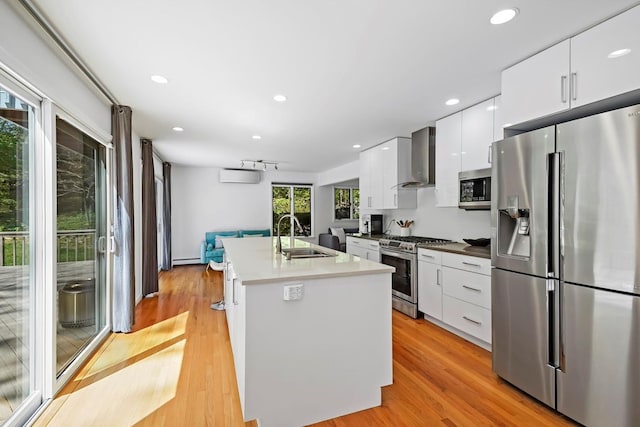 kitchen featuring white cabinets, a sink, wall chimney exhaust hood, stainless steel appliances, and modern cabinets