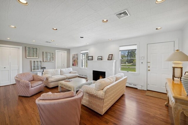 100 S Fairview Ave, Montauk, NY 11954 - living area with a warm lit fireplace, dark wood-style flooring, a healthy amount of sunlight, and visible vents