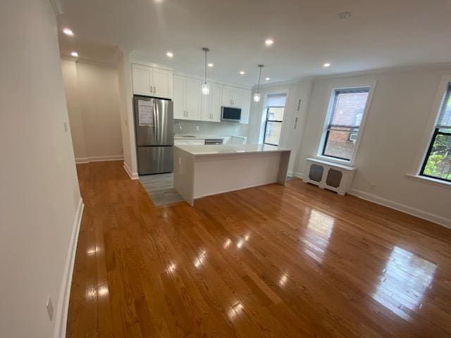 kitchen with wood finished floors, baseboards, light countertops, white cabinets, and stainless steel appliances