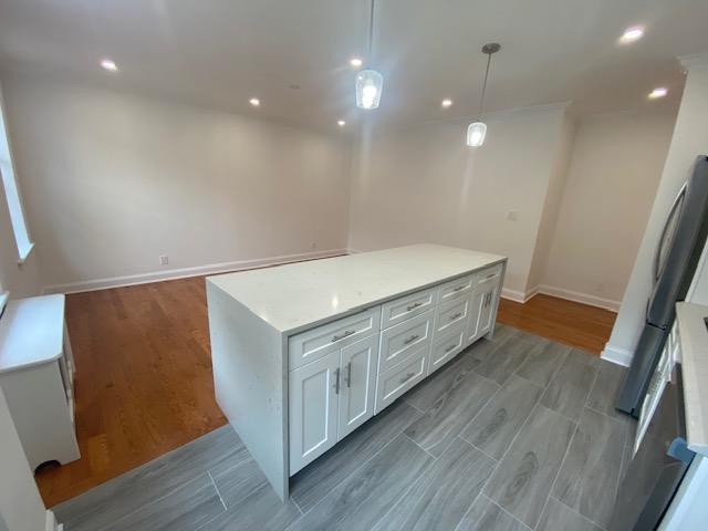 kitchen featuring light wood-style floors, baseboards, pendant lighting, and white cabinetry