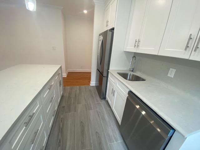 kitchen with a sink, appliances with stainless steel finishes, white cabinets, and baseboards