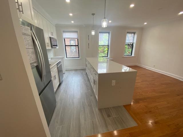 kitchen featuring wood finished floors, baseboards, light countertops, white cabinets, and stainless steel appliances