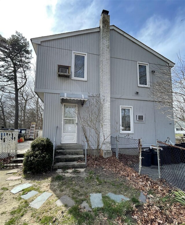 rear view of house with a chimney, fence, and entry steps