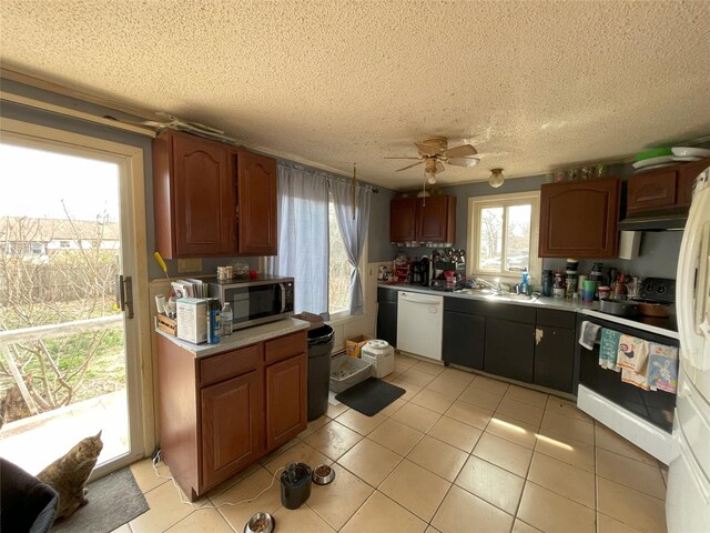 kitchen with light countertops, stainless steel microwave, a sink, dishwasher, and range with electric cooktop
