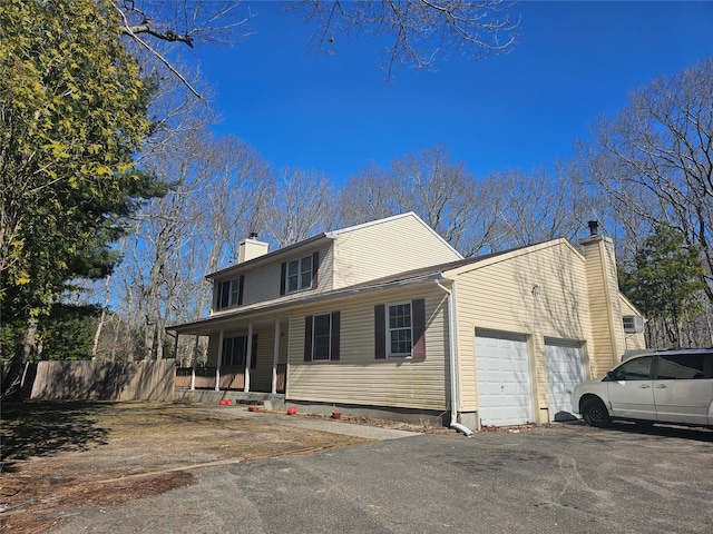 view of front of house with aphalt driveway, fence, a chimney, an attached garage, and covered porch