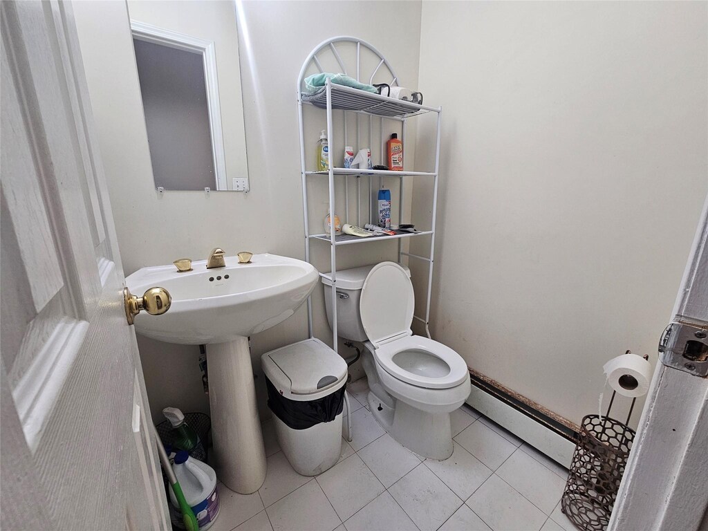 half bathroom with tile patterned flooring, toilet, and baseboard heating