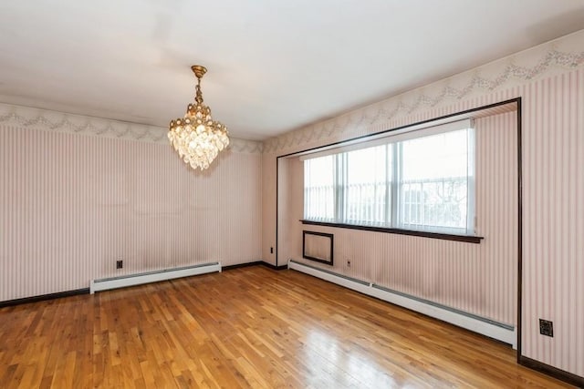empty room featuring a chandelier, hardwood / wood-style flooring, and baseboard heating