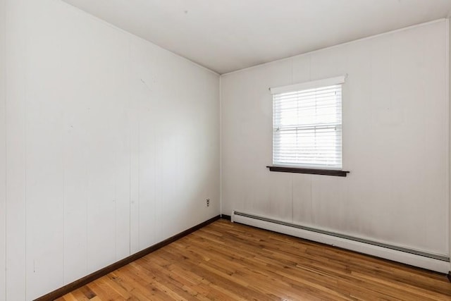 unfurnished room featuring light wood finished floors and a baseboard radiator