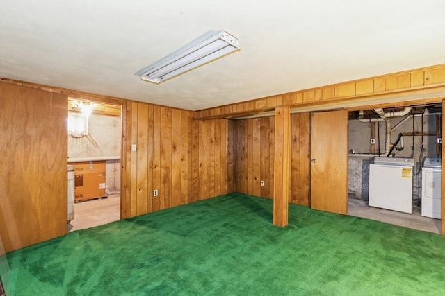 finished below grade area featuring carpet floors, wood walls, and washer and clothes dryer