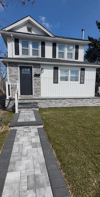 view of front of house with a front yard and stone siding