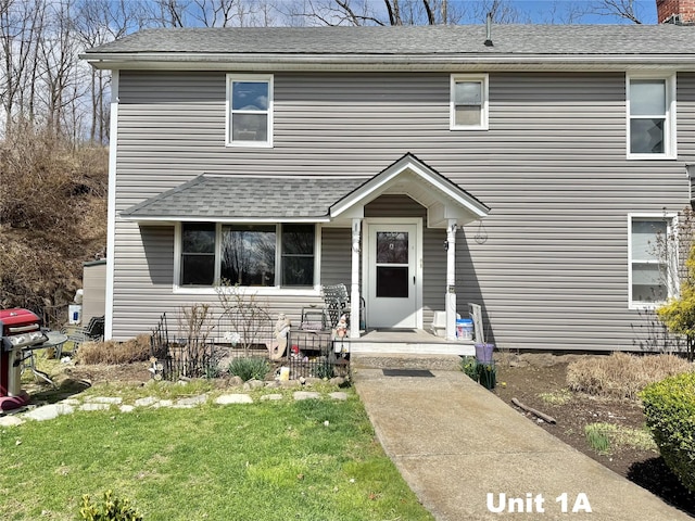 view of front of property with roof with shingles, a chimney, and a front yard