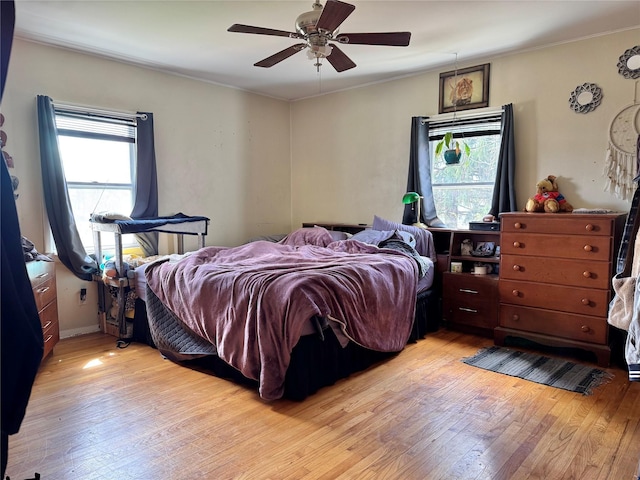 bedroom with light wood-style floors, multiple windows, crown molding, and a ceiling fan