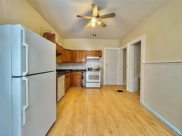 kitchen featuring dark countertops, white appliances, a ceiling fan, brown cabinetry, and light wood-style flooring