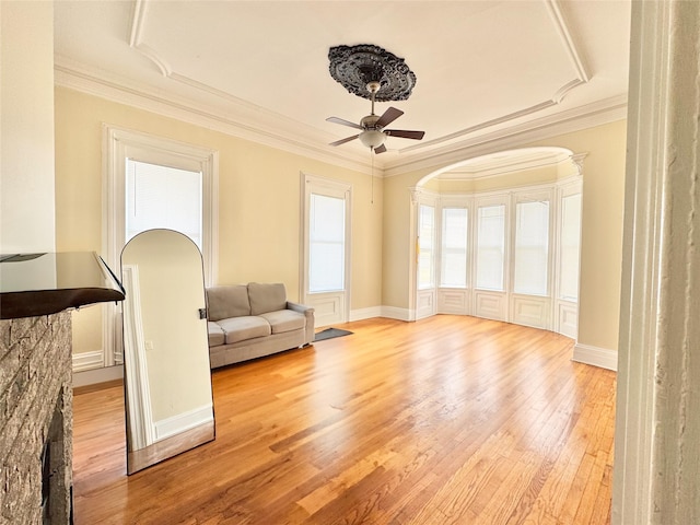 unfurnished living room with a ceiling fan, crown molding, and wood finished floors