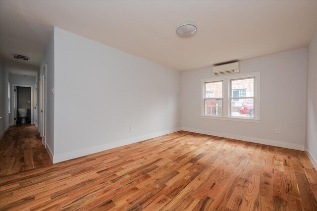 2738 Miles Ave, Bronx, NY 10465 - spare room featuring baseboards, wood finished floors, and an AC wall unit