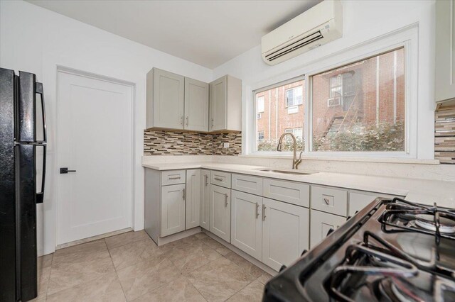 2738 Miles Ave, Bronx, NY 10465 - kitchen featuring light countertops, tasteful backsplash, a wall mounted air conditioner, a sink, and black appliances
