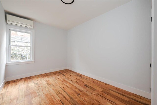 2738 Miles Ave, Bronx, NY 10465 - empty room featuring baseboards, a wall mounted AC, and light wood-style floors
