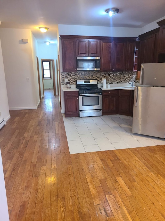 1871 Prospect Pl, Brooklyn, NY 11233 - kitchen with decorative backsplash, light countertops, light wood-style flooring, and appliances with stainless steel finishes