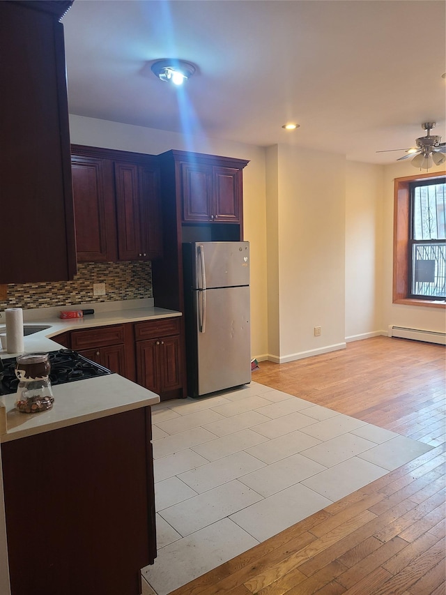 1871 Prospect Pl, Brooklyn, NY 11233 - kitchen with light countertops, cooktop, tasteful backsplash, a baseboard heating unit, and freestanding refrigerator
