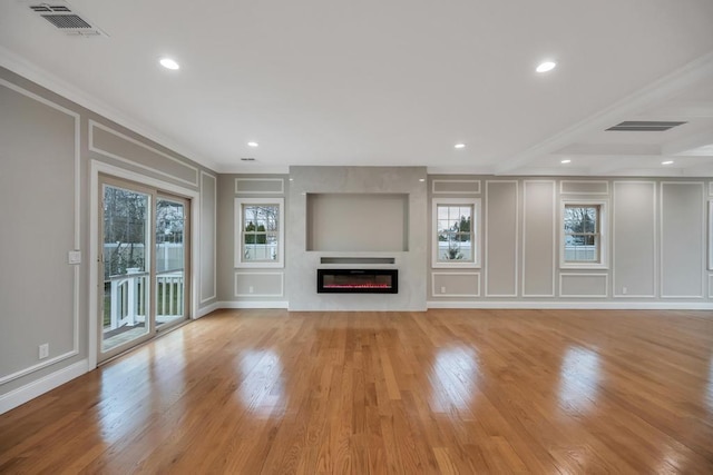 23 Grouse Ln, Levittown, NY 11756 - unfurnished living room featuring crown molding, a glass covered fireplace, visible vents, and a decorative wall