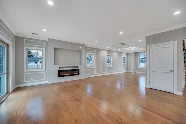 23 Grouse Ln, Levittown, NY 11756 - unfurnished living room featuring a glass covered fireplace, light wood-style flooring, baseboards, ornamental molding, and visible vents