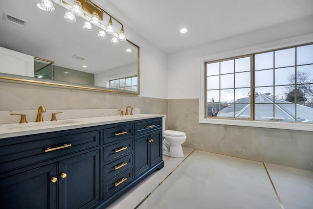 23 Grouse Ln, Levittown, NY 11756 - bathroom with visible vents, a wainscoted wall, toilet, and a sink
