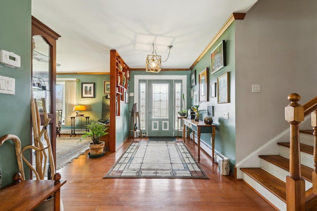 entrance foyer with ornamental molding, stairway, a baseboard radiator, baseboards, and hardwood / wood-style flooring
