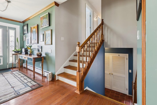 entrance foyer with baseboards, ornamental molding, wood finished floors, stairs, and a baseboard heating unit
