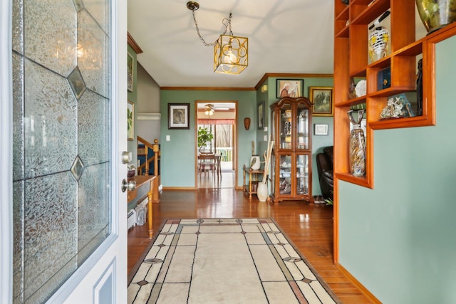 corridor with baseboards, ornamental molding, a chandelier, stairway, and wood finished floors