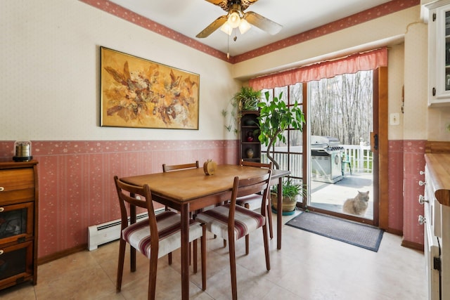 dining area featuring wainscoting, wallpapered walls, and a ceiling fan