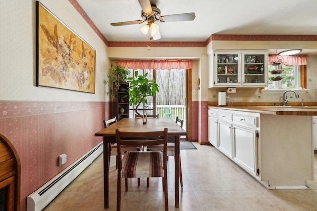 dining room featuring baseboard heating, a healthy amount of sunlight, ceiling fan, and wallpapered walls