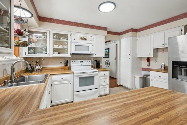 kitchen featuring glass insert cabinets, white cabinets, a sink, white appliances, and butcher block countertops