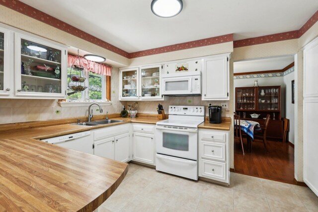 kitchen with white appliances, white cabinetry, a sink, and decorative backsplash