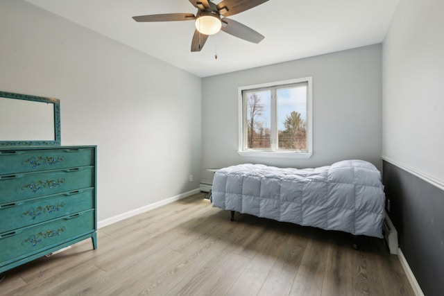 bedroom with ceiling fan, light wood finished floors, and baseboards