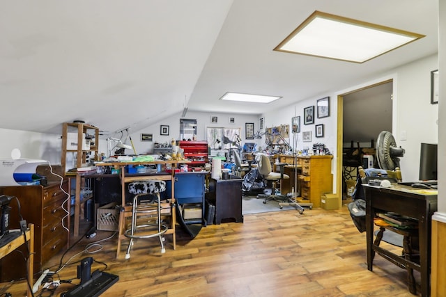 office area featuring vaulted ceiling, wood finished floors, and a workshop area