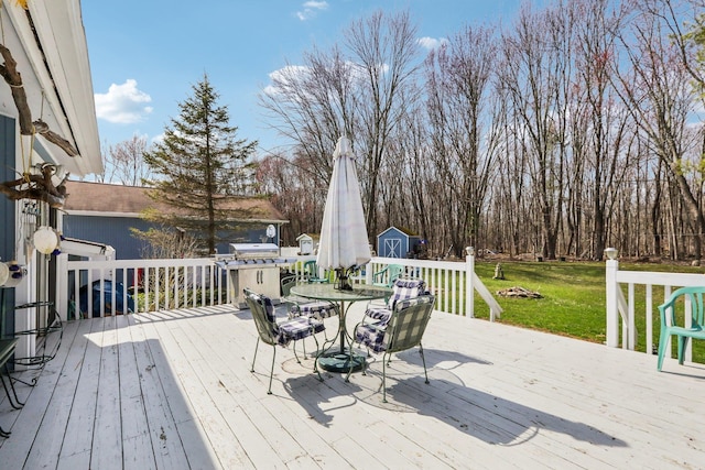 deck with a lawn, an outdoor structure, area for grilling, and a storage unit