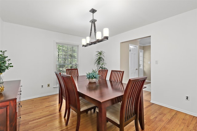dining room with baseboards, an inviting chandelier, and light wood-style floors