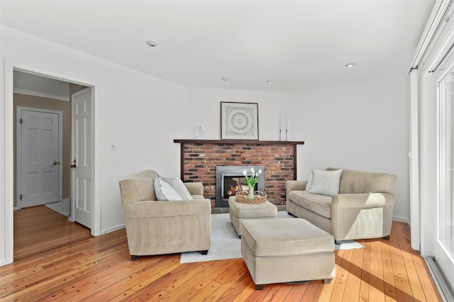living area featuring baseboards, recessed lighting, light wood finished floors, and a brick fireplace