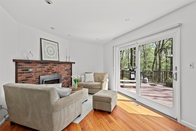 living room with baseboards, a fireplace, hardwood / wood-style floors, and visible vents