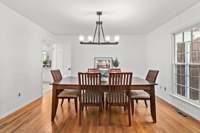 dining space with baseboards, a notable chandelier, light wood finished floors, and visible vents