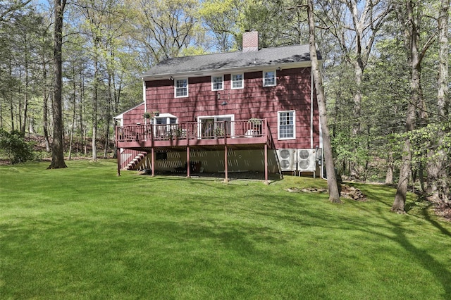 back of property with a wooden deck, a chimney, stairs, a shingled roof, and a yard