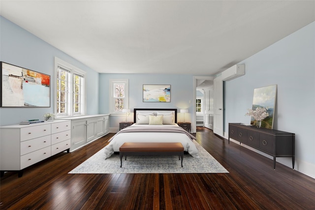 bedroom featuring dark wood-style flooring, an AC wall unit, and baseboards