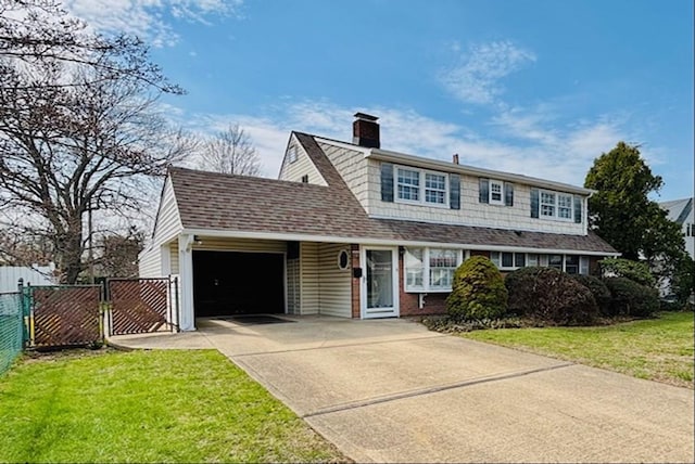 traditional-style home featuring a front lawn, a chimney, concrete driveway, fence, and an attached garage