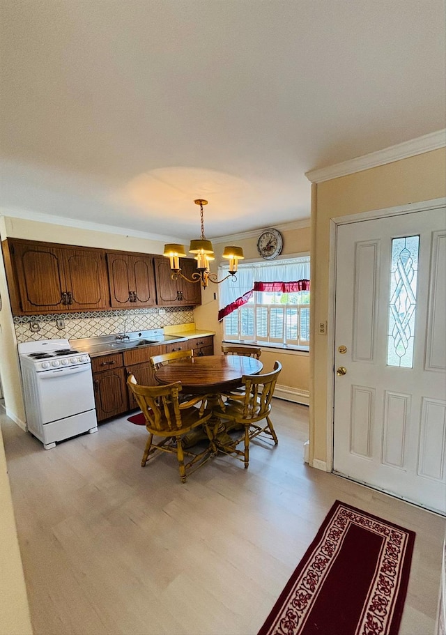 dining room with baseboards, an inviting chandelier, crown molding, and light wood-style flooring