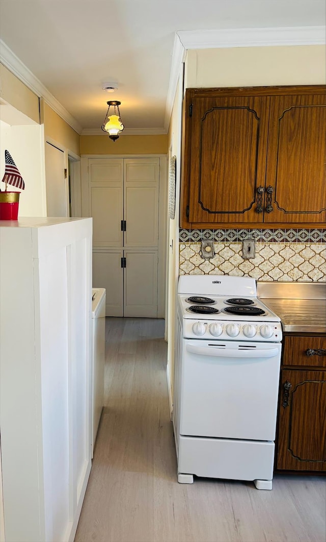 kitchen featuring white electric range oven, light wood-style floors, light countertops, backsplash, and ornamental molding