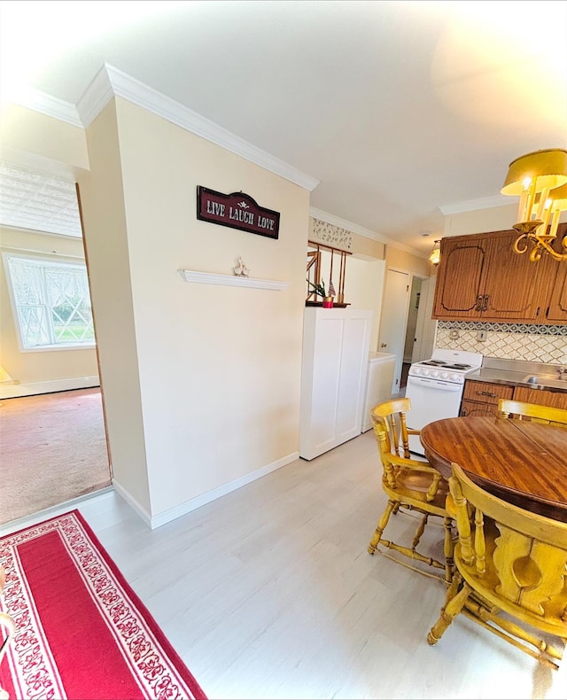 dining room with light wood-style flooring, baseboards, a chandelier, and ornamental molding